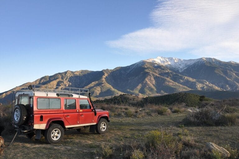 top 11 des meilleurs road trips au monde une jeep sur une falaise avec vu de la montagne